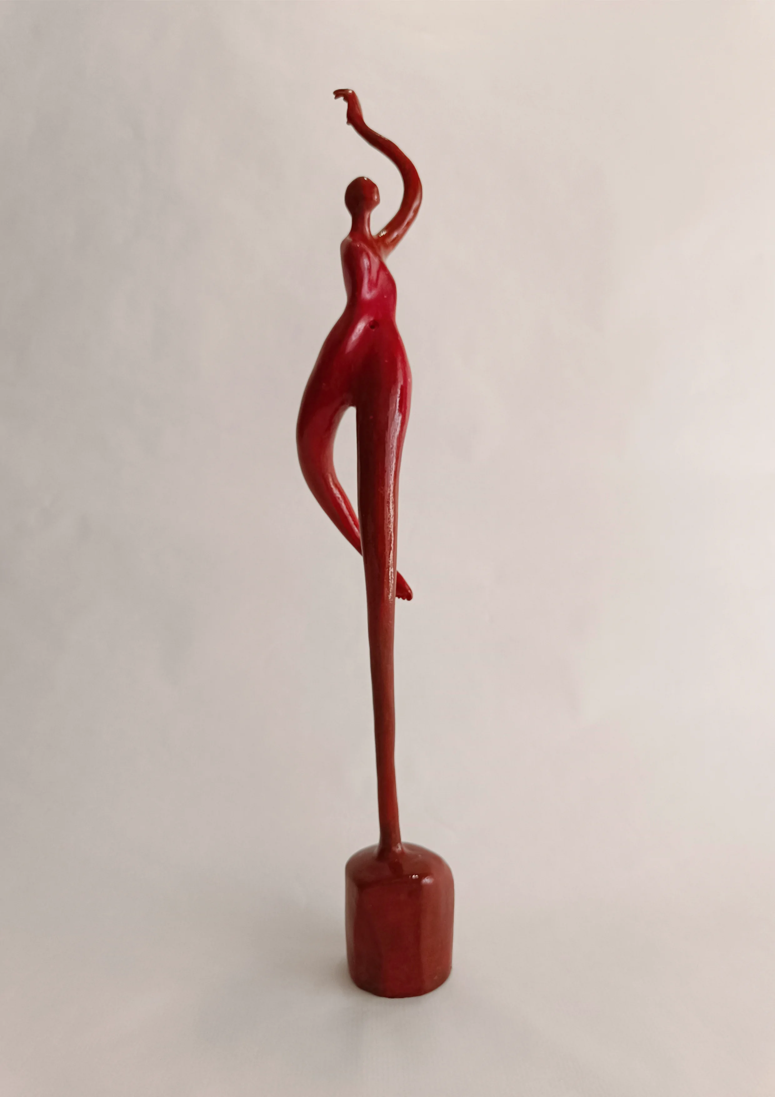 Figura en pie con un apoyo y brazo levantado. Tonos rojos. 46x9x8 centímetros. 520 gramos